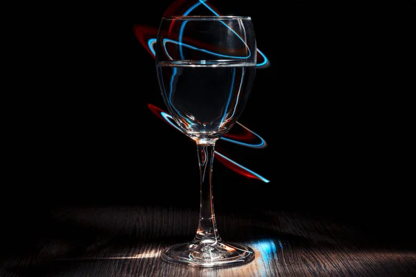 A transparent glass of wine with a liquid. Light effect. — Stock Photo, Image