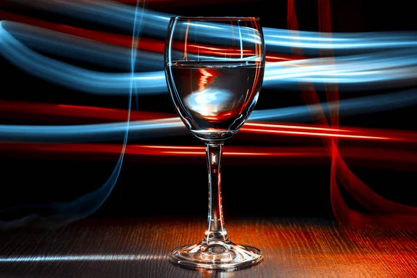 A glass of wine in a nightclub. Red and blue light effect.Blue blurred stripes. — Stock Photo, Image