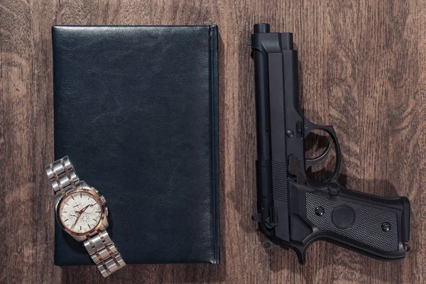 Brott bakgrunden av bakgrund. Gun, handväska och armbandsur. Ovanifrån. — Stockfoto