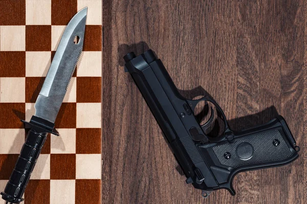 Kriminella set. Kniv på en schack-tabell. Pistolen är nära. — Stockfoto