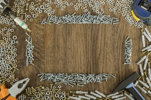 Background or background of short metal nuts and screws. Work tools are located at corners. — Stock Image Background or background of short metal nuts and screws. Work tools are located at corners. Stock Picture