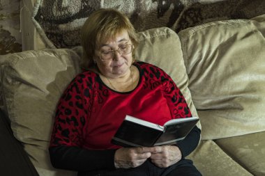 Bir kadın kanepede oturan bir kitap okuyor.