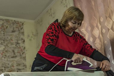 Yaşlı bir kadın elbise Ütü.