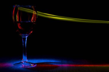 Bir kadeh şarap. Kırmızı, sarı ve mavi ışık efekti .