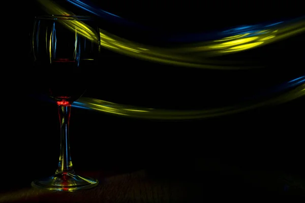 Bir bardak kırmızı şarap gece kulübü. Mavi ve sarı bulanık bantları. — Stok fotoğraf