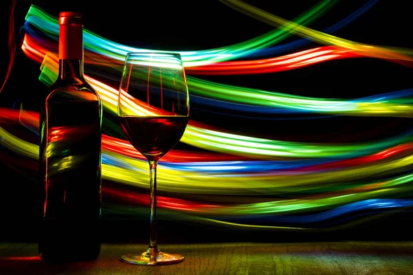 Fles en een glas wijn op lichte achtergrond met bokeh effect. — Stockfoto