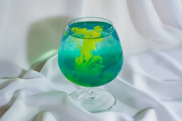 Green watercolor in a glass. Color mix in the glass. Oil paint in water. — Stock Photo, Image