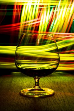 Bir bardak konyak bokeh etkisi ile parlak arka plan üzerinde.