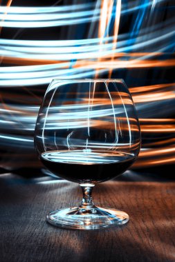 Bir bardak konyak bokeh etkisi ile parlak arka plan üzerinde.