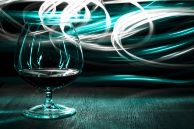 Bir bardak konyak parlak arka plan ışığı efekti üzerinde.