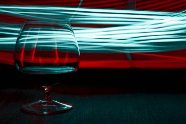 Bir bardak konyak parlak arka plan ışığı efekti üzerinde.