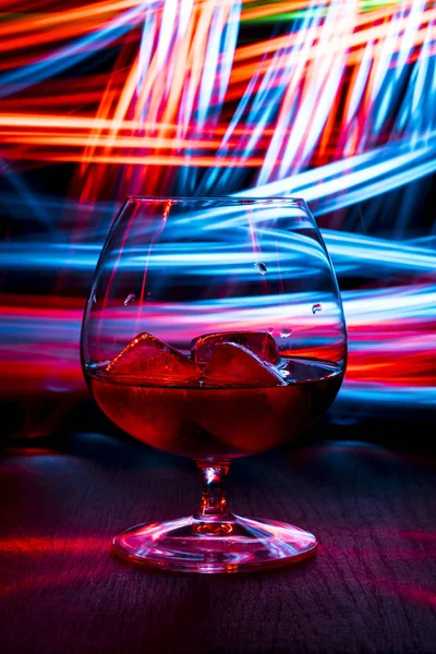Pohár whiskyt az asztalra. Sötét háttér bokeh hatása. — Stock Fotó