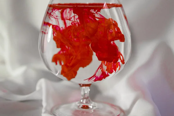 Kırmızı suluboya bir cam. Renk karışımı cam. Suda boya. Renkli kokteyl.