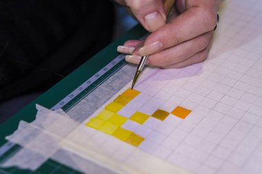 Bir fırça ile bir el kağıt üzerinde hücreleri boyar.