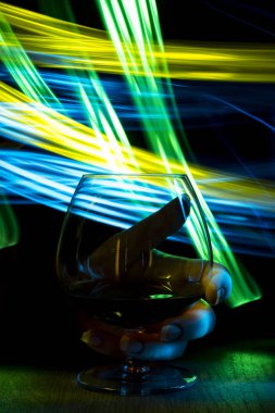 Bir bardak konyak bokeh etkisi ile elinde.