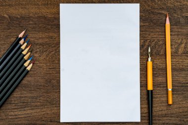 Arka plan veya arka plan kalemler üzerinde ahşap bir masa. Merkezi temiz beyaz bir levha.