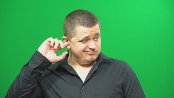 Junger Mann posiert. Ein Mann prüft sein Ohr mit einem Finger. Hintergrund Green Screen. — Stockvideo