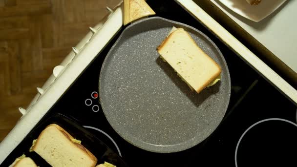 Gros plan des mains préparer des sandwichs dans la cuisine. Faire frire trois billettes dans une poêle . — Video