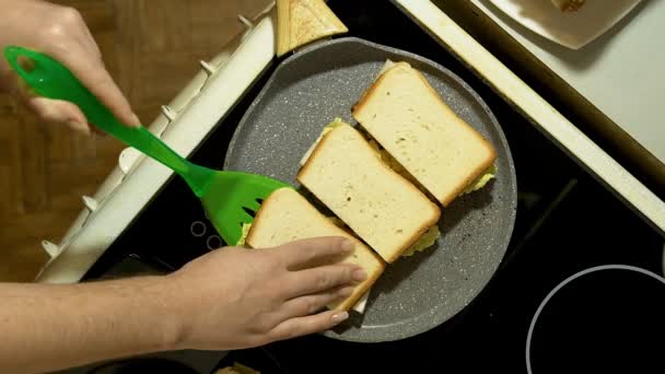 In der Küche bereiten Hände Sandwiches zu. Drei Knüppel in einer Pfanne braten. — Stockvideo