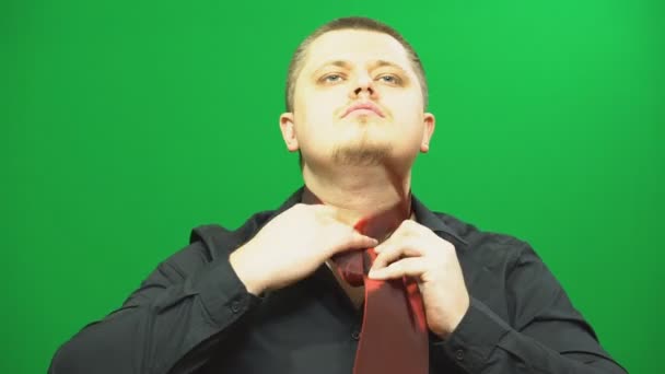 A fiatalember hoz létre. Kipróbálás-hoz nyakkendőt kötni a nyakán. Zöld háttér. — Stock videók