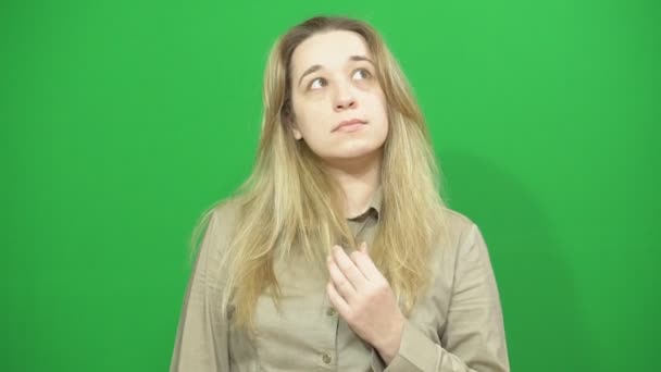 Young girl posing. She looks at the camera and looks around. The background green. — Stock Video