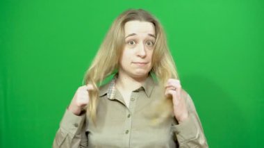 Genç kız poz. İyi bir ruh hali. O gülümsüyor ve etrafına bakıyor. Elleriyle saçlarını düzeltiyor. Arka plan yeşil ekran.