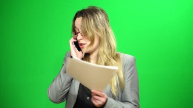 Elinde kağıt üzerine notlar ile müdürü. Cep telefonundan konuşuyor. Sinirli ve tedirgin.