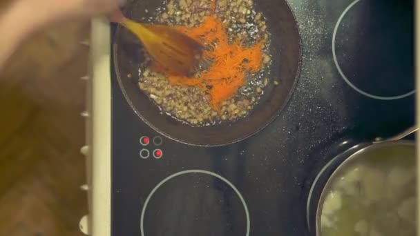 Voorbereiding van zelfgemaakte soep benadert. Hot pot op het fornuis. Voeg de gehakte wortelen. Fry. — Stockvideo