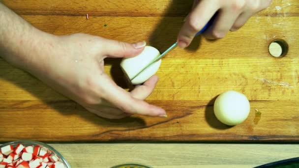 Un cocinero trabaja con un cuchillo en una tabla de cocina amarilla. Cortar huevos cocidos . — Vídeos de Stock