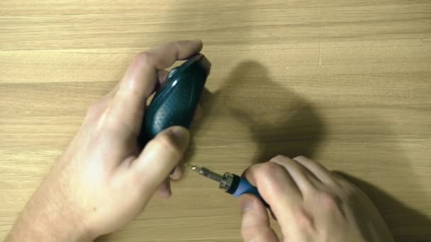 Closeup of a hand to disassemble a computer mouse. We unscrew the screws with a screwdriver. — Stock Video