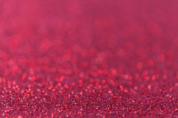 Red sparkling background from small sequins, closeup. Brilliant backdrop