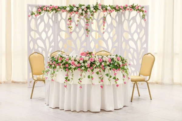 Hlavní tabulka novomanželé, zdobený květinovým složením a oblouk v pastelových barvách — Stock fotografie