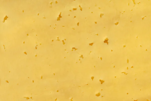 Een stuk gele kaas met gaten close-up. — Stockfoto