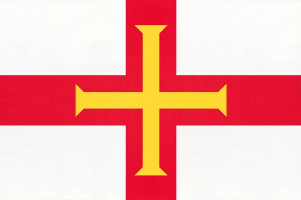 Guernsey isola bandiera nazionale tessuto con emblema, sfondo tessile . — Foto Stock