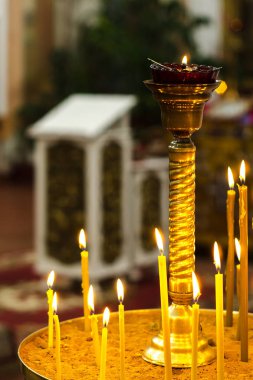 Kilisede bir kaide üzerinde duran sarı mum yakma