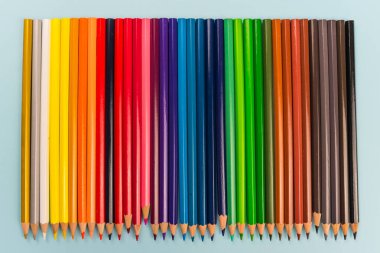 Renkli kalemler açık mavi arkaplanda izole edildi. Kapatın. Mavi arka planda izole edilmiş renkli kalem, eğitim çerçevesi kavramı. arka plan mavi kağıttaki renkli kalemlerden. Renkli kalemlerden oluşan renkli bir çizgi. resim