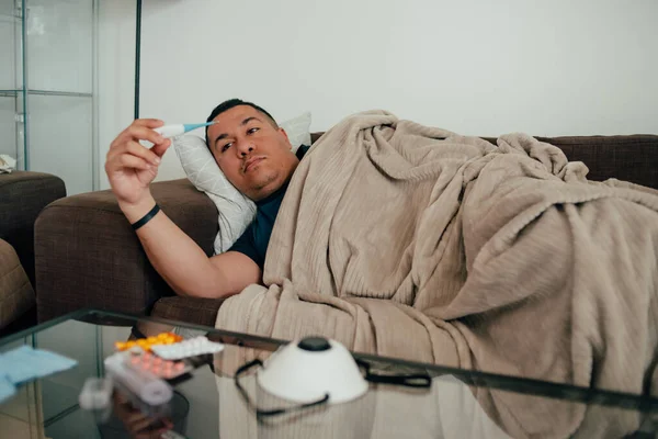 Ateşle yatakta yatan hasta bir adamın portresi. Genç hasta adam soğuk algınlığı ve grip yüzünden yatakta yatıyor, termometredeki sıcaklığa bakıyor. Üzgün adamlar yatakta yatar ve termometreyi tutarlar. Hastalık konsepti.