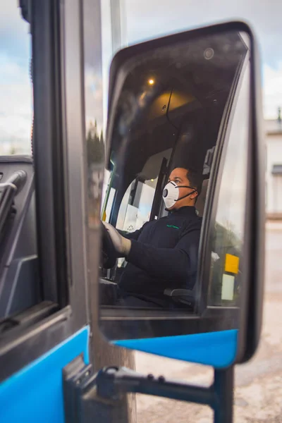 young hispanic bus driver with mask puts protecting gloves on his hand in bus to protect himself from the coronavirus epidemic. covid 19. protect from corona virus. quarantine 2020. stay home.