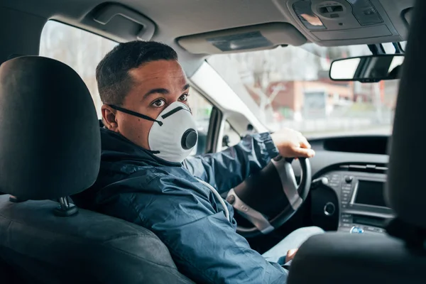 Genç İspanyol adam arabada yalnız. Koronavirüsün yayılmasını önlemek için koruyucu maske takıyor. Genç İspanyol taksi şoförü koruyucu bir maske takıyor ve müşteri bekliyor. Coperid 19. Coronavirüs. Epidemi. pandemia.