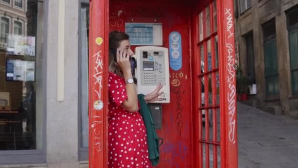 Mujer joven está hablando por teléfono móvil en la cabina de teléfono — Vídeos de Stock