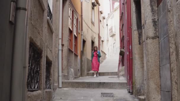 Гарненька жінка мандрівник ходить старою вузькою вулицею за допомогою навігації на гаджеті — стокове відео