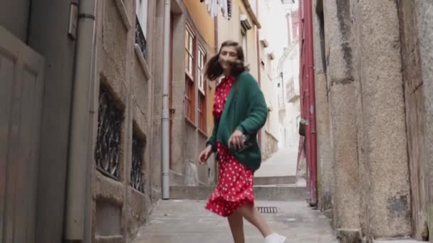 Гарненька жінка працює на старій вузькій вулиці, дивлячись назад на камеру — стокове відео