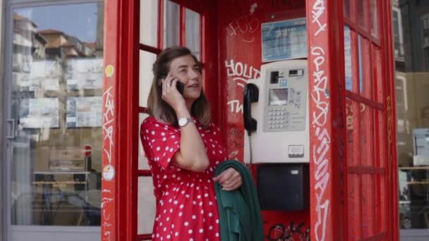 Jonge vrouw, student is in gesprek op mobiele telefoon in de telefooncel — Stockvideo