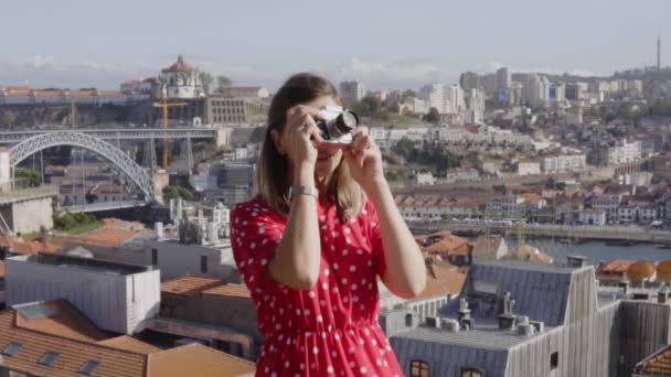 Mulher de vestido vermelho está tirando uma foto na câmera vintage — Vídeo de Stock