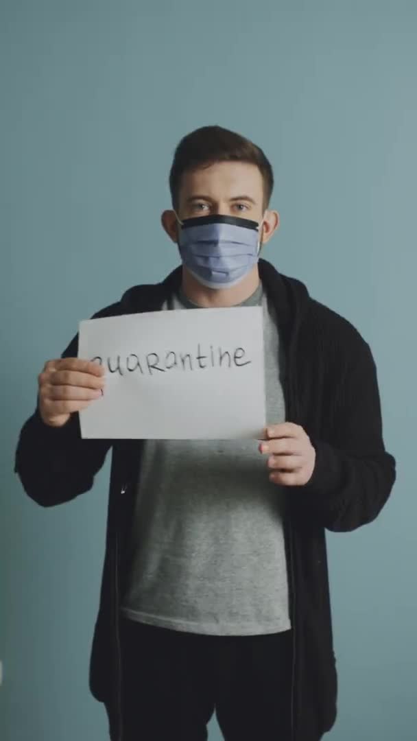 Un jeune homme en masque de protection tient une affiche de quarantaine — Video