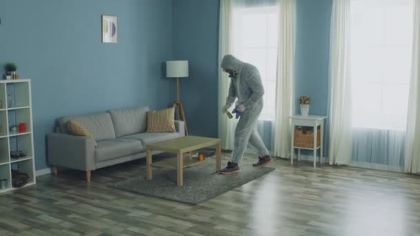 Человек в защитной одежде дезинфицирует свой дом — стоковое видео