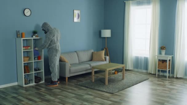 Человек в защитной одежде дезинфицирует квартиру — стоковое видео