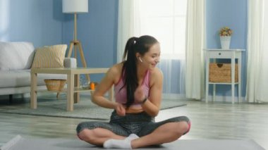 Kadın Fitness Mat 'te oturuyor ve dans ediyor.