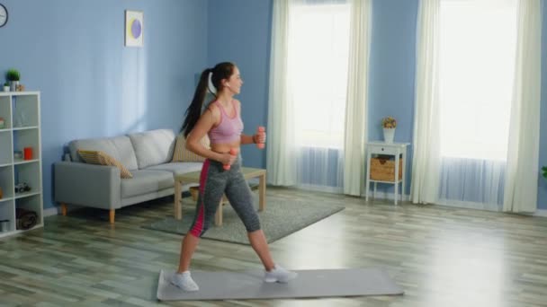 Mujer joven está entrenando con pesas — Vídeo de stock