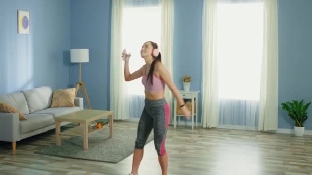 Mujer bonita está bailando en casa, sosteniendo un vaso de agua — Vídeos de Stock